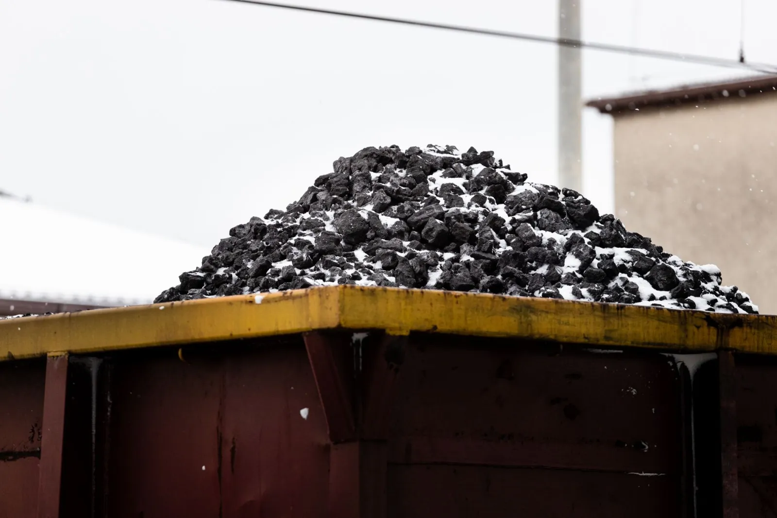 A heap of coal on a freight train car covered with snow, symbolizing transport and industry.